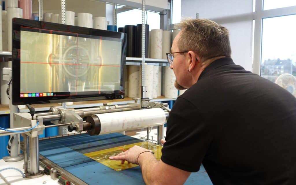 Salarié de Filpack montant un cliché sur un manchon adhésif 